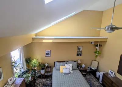 Loft bedroom repainted in a cheerful yellow hue called Cellini Gold by Behr